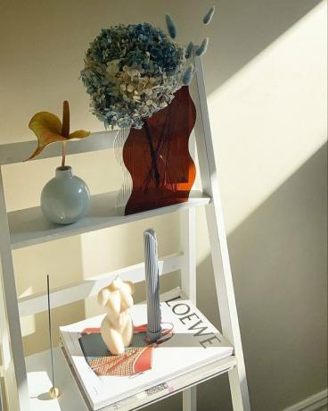 uma prateleira decorada com velas, livros de mesa de centro e vacas