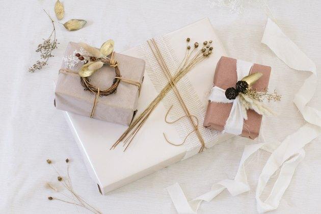Pacotes com papel marrom, branco e neutro com fita branca e flores secas