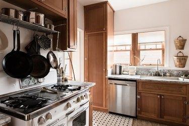 gaskomfur og støbejernsgryder i et minimalistisk køkken med sort-hvide gulvfliser
