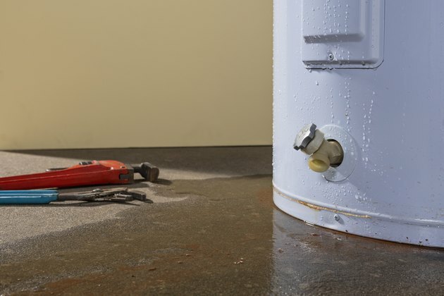 Un calentador de agua doméstico residencial gotea con herramientas de plomería