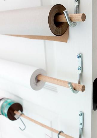 ideia de armazenamento de papel de embrulho na parte de trás da porta com cavilhas de madeira