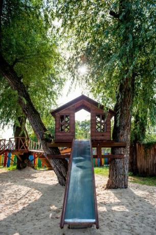 casa del árbol con un tobogán en el patio de recreo