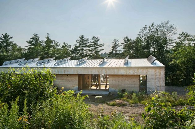 Moderne prefab woning met zonnepanelen omgeven door bomen