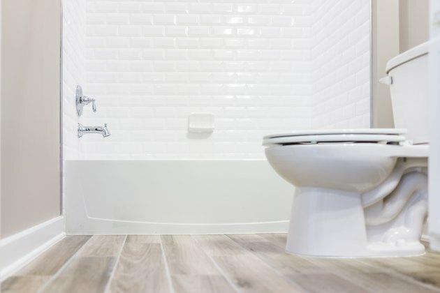Banheiro moderno, branco, limpo e limpo, com chuveiro e piso de madeira no nível do solo