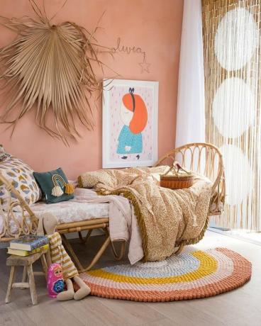 boho meisjeskamer met rotan bed en kralengordijn met roze muren