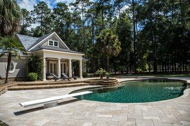 Pool House sur mesure derrière un domaine paysager avec une grande piscine et un bain à remous