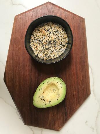 Houten bord met kruiden in zwarte kom en avocado