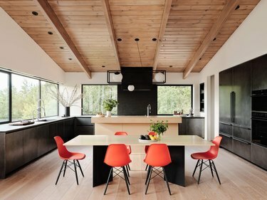 почернена стоманена кухня с дървен таван и оранжеви столове