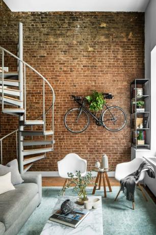 estilo industrial apartamento sala de estar com parede de tijolos expostos e escada em espiral