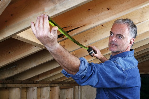 Mann som måler avstand mellom rafterbjelker i hjemmetillegg.