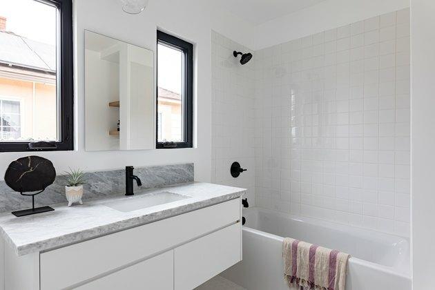 banheiro com chuveiro / banheira combinados; vaidade do banheiro; esquema de cores cinza, branco e preto