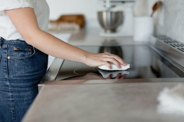 Namų valymo idėjos, kai moteris virtuvėje valo krosnį