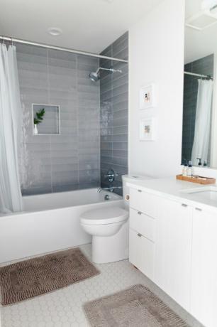 piso de ladrilho hexagonal branco, pia de banheiro branco, vaso sanitário branco, banheira branca com parede de chuveiro cinza