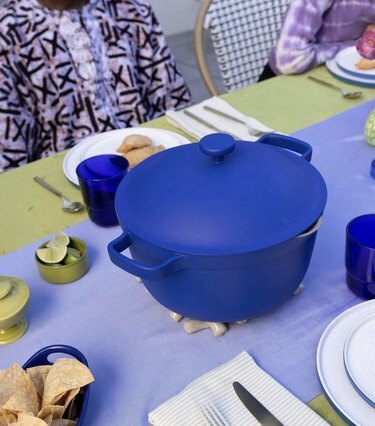 Mėlynas Perfect Pot ant stalo su šviesiai mėlyna ir žalia staltiese. Yra tortilijos traškučiai ir mažas žalias dubenėlis laimų kartu su stalo servizais.