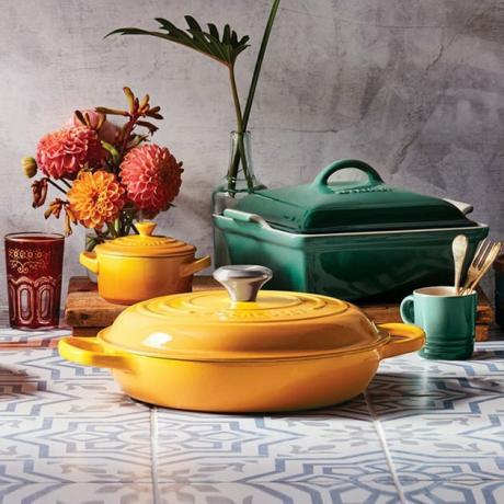 le creuset virtuves piederumi uz rakstainas virsmas ar tuvumā esošiem ziediem