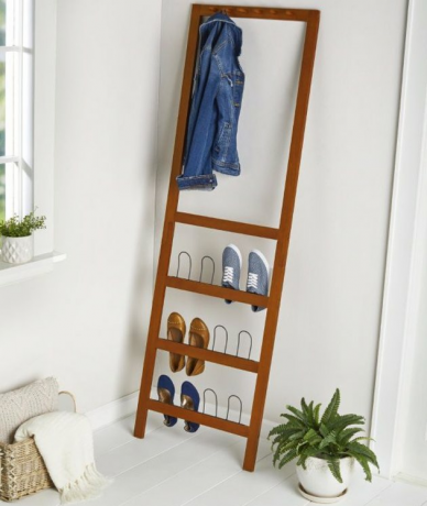 Organizador de sapatos de madeira e cabide, planta em vaso branco, cobertores na cesta.