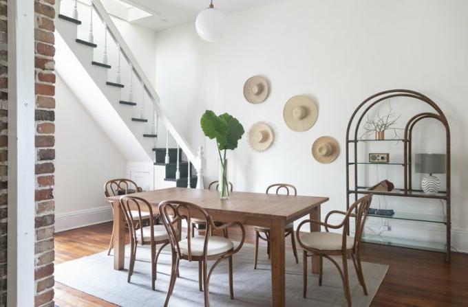 Sala da pranzo con tavolo in legno e cappelli di paglia appesi sulla parete