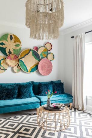 maximalistische woonkamer met blauwe bank en mand wandkleden