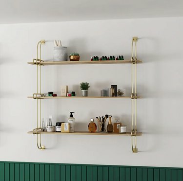 Zwevende houten planken met gouden hardware op een witte muur