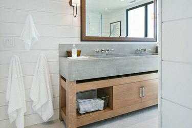 Kupaonica s betonskim sudoperom, bijeli zidovi.