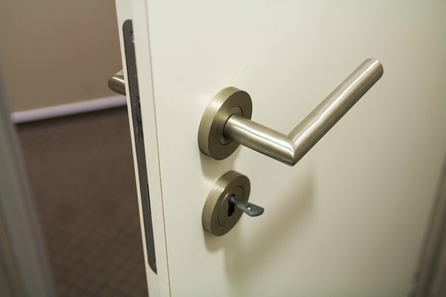 Sluit omhoog van lichtjes open nieuwe witte plastic deur met helder glanzend handvat en sleutels in het slot. Veiligheid en beveiliging van huis, kantoor.