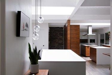 Mūsdienīga minimālisma virtuve ar globusa piekarināmiem lukturiem un baltiem letes ar koka skapjiem.