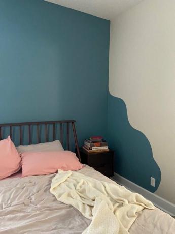 cama com roupa de cama neutra e travesseiros rosa perto da parede ondulada