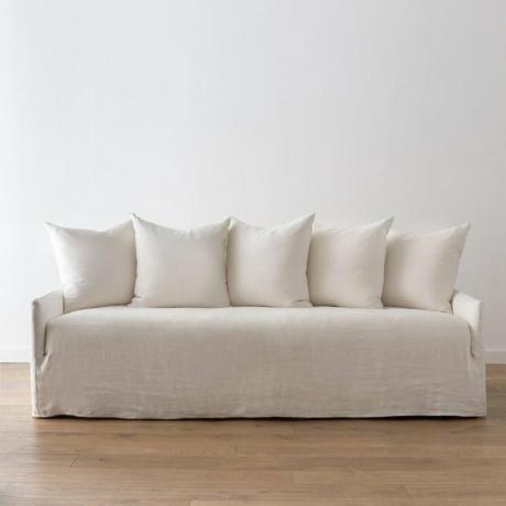 sofá costeiro slipcovered com coleção de travesseiros traseiros por Amber Interiors