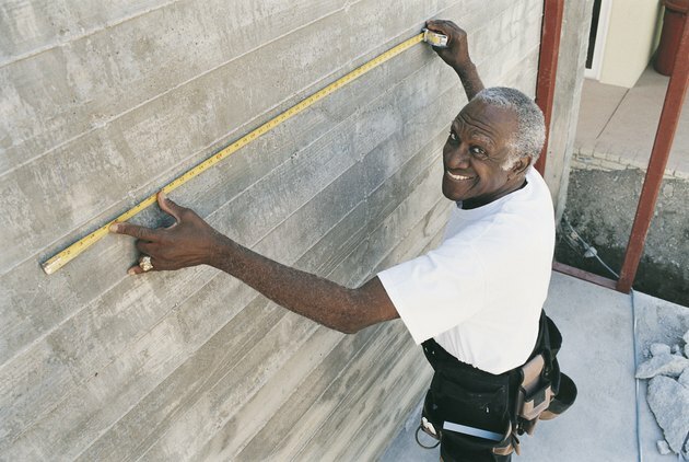 Forhøjet udsigt over en mand, der måler en væg med et målebånd