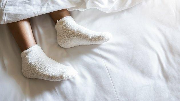 Seção baixa da mulher vestindo meia relaxante na cama