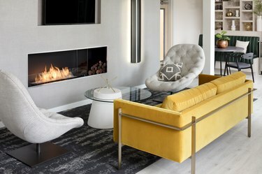 espaço da sala de estar com sofá amarelo, cadeiras brancas e lareira