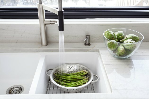 Lavare gli asparagi freschi nel lavello della cucina.