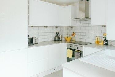 valkoinen minimalistinen u-muotoinen keittiö keltaisilla yksityiskohdilla