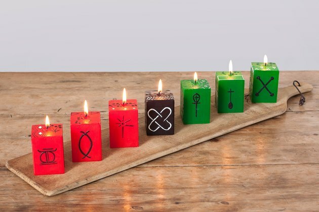 Decorações de kwanzaa, velas em cubos de kwanzaa vermelhas, verdes e pretas em uma placa de madeira