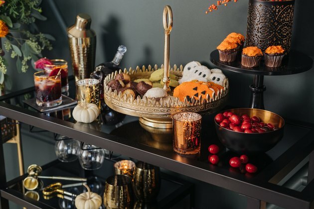 Fall Party-idee met barwagen en gouden cocktailset en caketribune met Halloween-koekjes