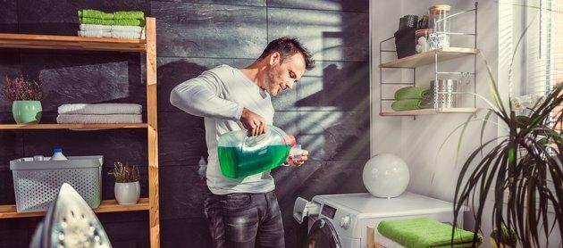 Človek natoči detergent za perilo
