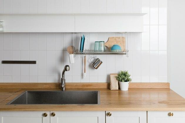 Nettoyer la vaisselle en séchant sur une grille en métal sur fond clair. Ustensiles de cuisine et vaisselle sur étagère en bois. Fond intérieur de cuisine. Espace texte.