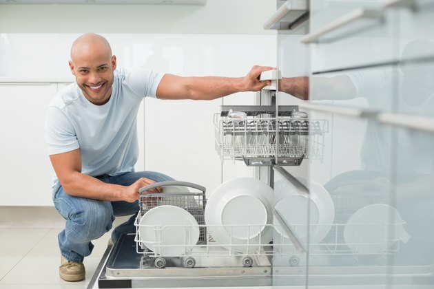 Portræt af en smilende mand, der bruger opvaskemaskine i køkkenet