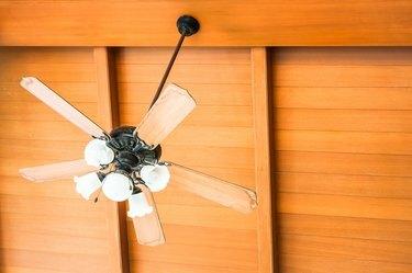 Низкий угол обзора электрического вентилятора, висящего на деревянном потолке