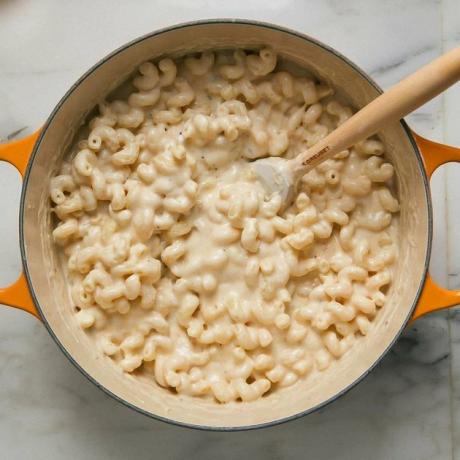 uma cozinha aconchegante assada mac e queijo em uma panela de laranja com colher de pau