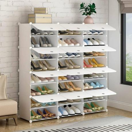 Organizador de sapato modular branco, tapete listrado, planta em vaso.