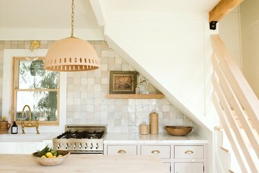висяща лампа над дървен кухненски остров в кухня с бежово покритие с плочки
