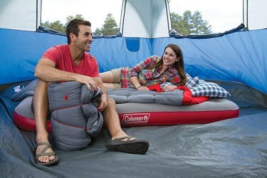 twee kampeerders in een blauwe tent zittend op een Coleman quickbed luchtbed