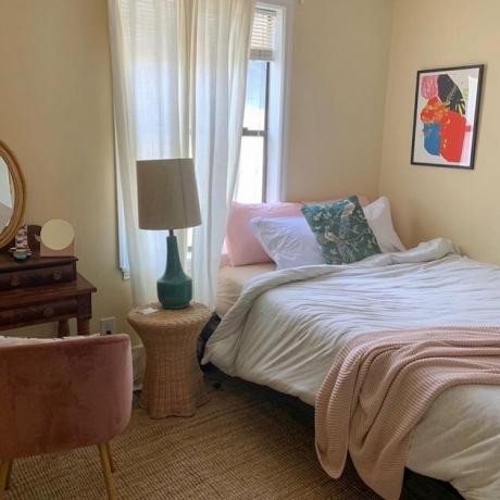 quarto com cama rosa e branca e obras de arte emolduradas