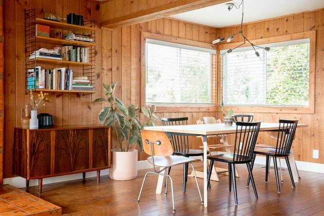 Moderna sala da pranzo Mid-Century con pareti in legno e tavolo con sedie non corrispondenti