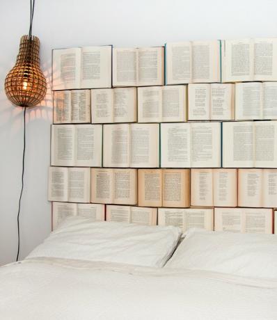 الكتب المفتوحة التي تسمر على الحائط بمثابة لوح رأس لسرير أبيض.