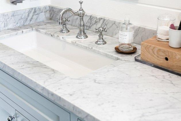 Benkeplate i marmor, hvit undermontert vask, sølvkran og håndtak