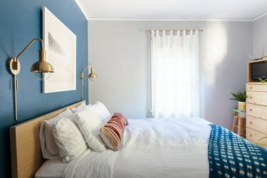 cama perto da parede azul com lençóis brancos e cobertor azul