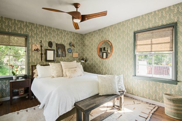 quarto com roupa de cama branca e paredes com papel de parede verde