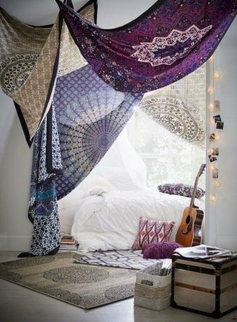 Boho slaapkamer met gedrapeerde wandtapijten door wit bed